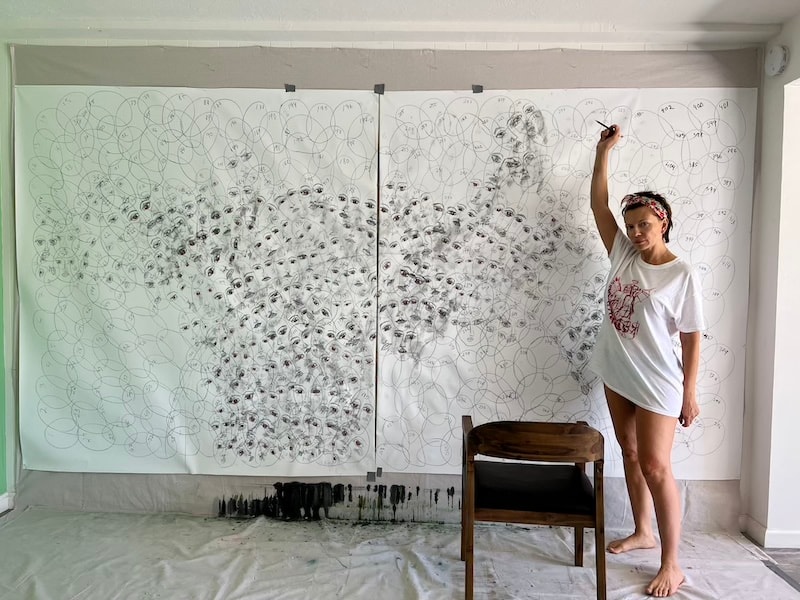Marina Orlova drawing on large wall mural in studio