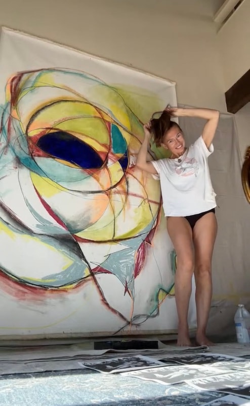 Marina Orlova posing with large abstract artwork in studio